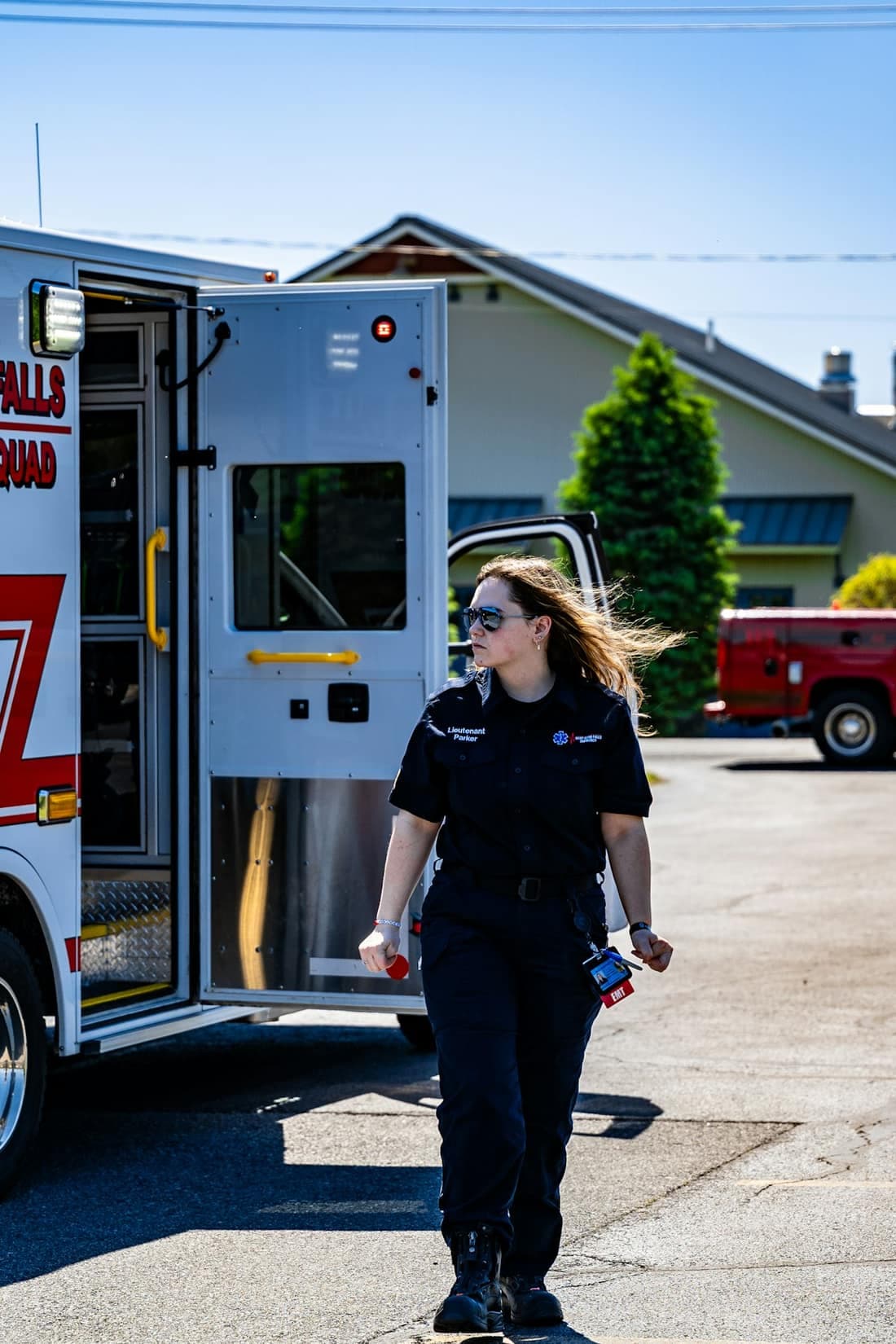 An EMT in uniform walking away from the open side door of an ambulance.